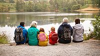 Eine Familie hock sitzt zusammen und schaut auf einen See