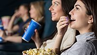 Frau sitzt im Kino und isst Popcorn